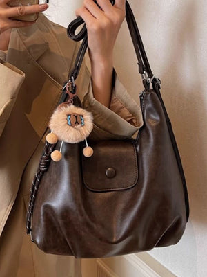 Vintage pu leather shoulder bag in olive brown with a front flap pocket and fuzzy charm.