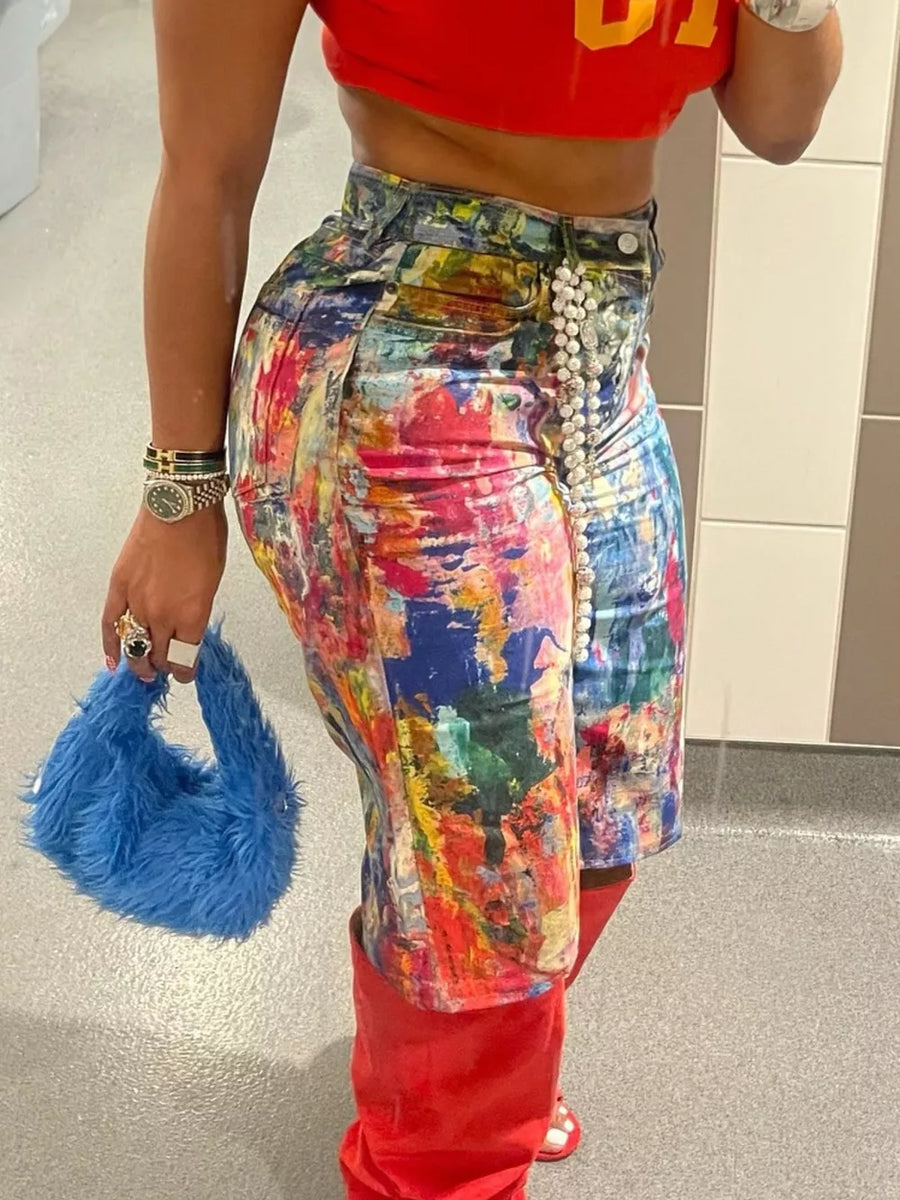 Denim shorts with abstract paint splatter pattern, pearl embellishment, and red boots.
