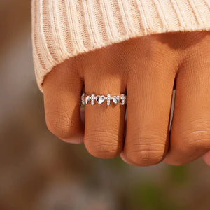 Sterling silver band ring with alternating heart and cross charms, adorned with small stones.