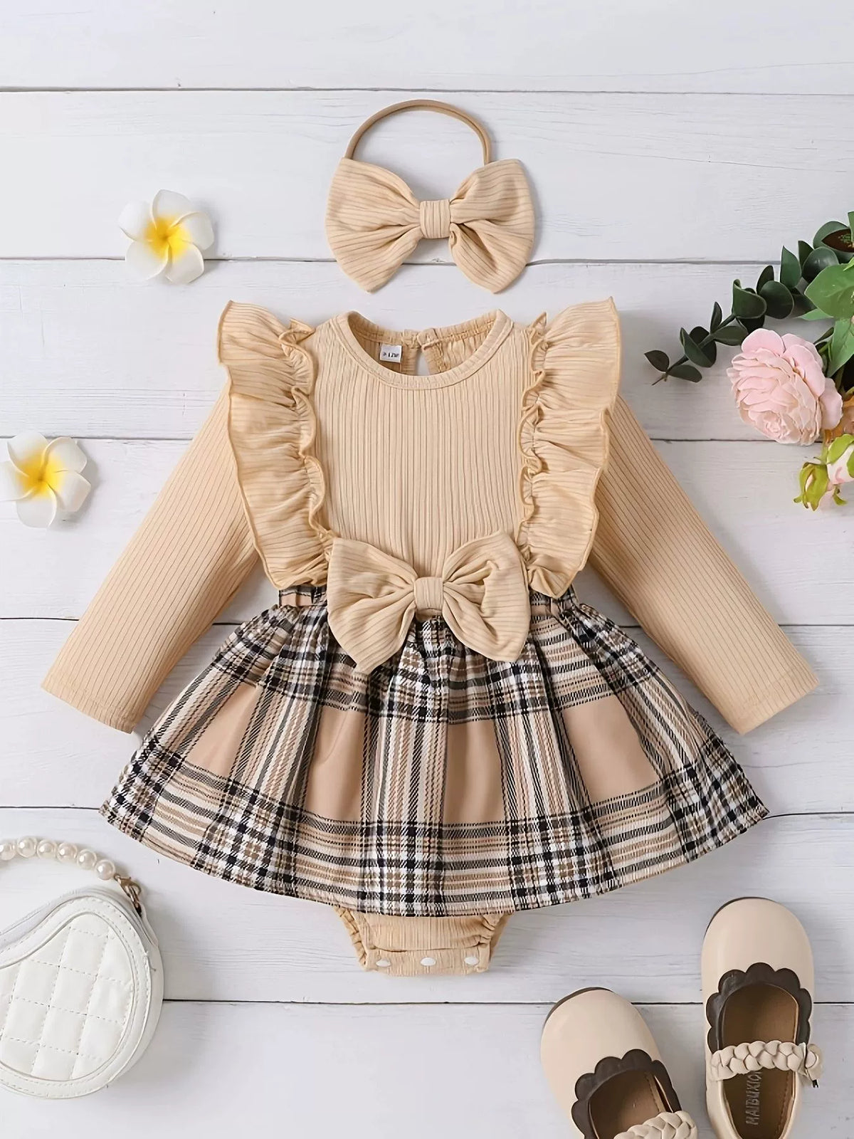 Baby girl's beige ruffled bodysuit with plaid skirt and bow, includes headband.