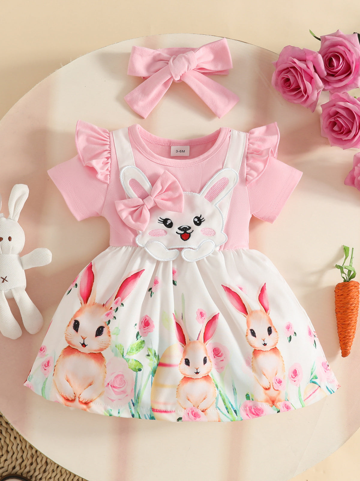 Pink baby dress with bunny applique, ruffled sleeves, and floral bunny print skirt. Includes matching bow headband.