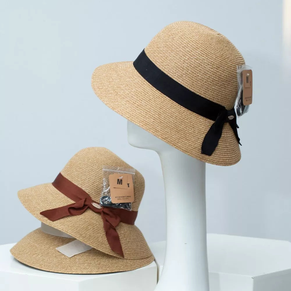 Straw bucket hat with downturned brim and ribbon detail in black or rust.