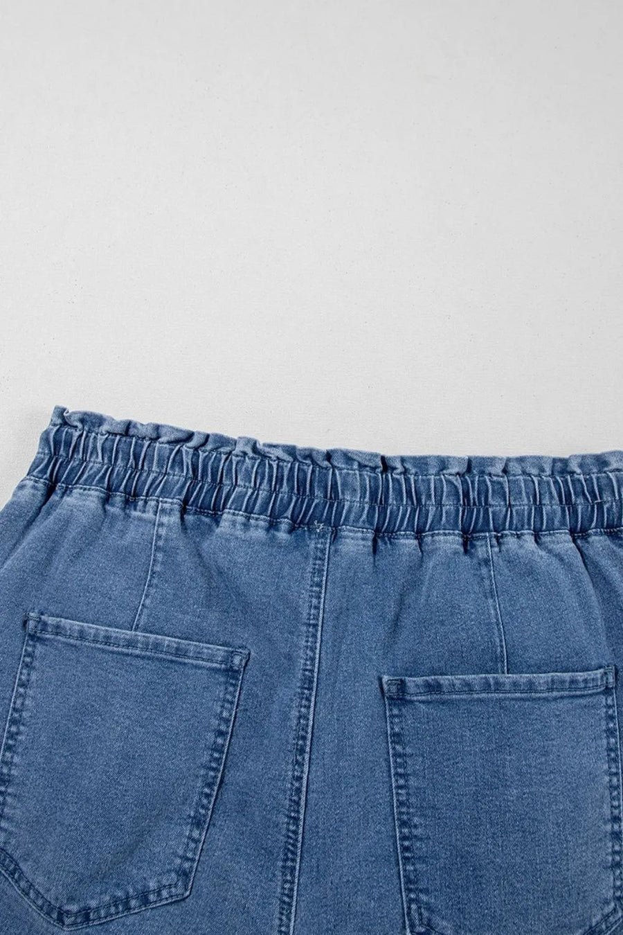 Medium wash denim shorts with paperbag waist and relaxed fit.