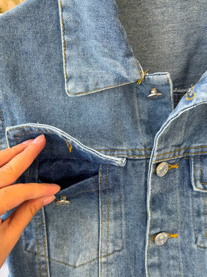 Chic buttoned denim jumpsuit with pockets and yellow stitching.
