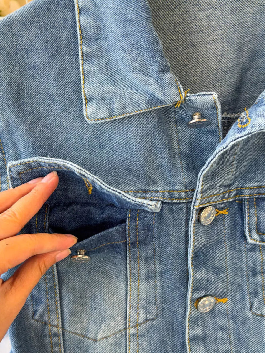 Chic buttoned denim jumpsuit with pockets and yellow stitching.