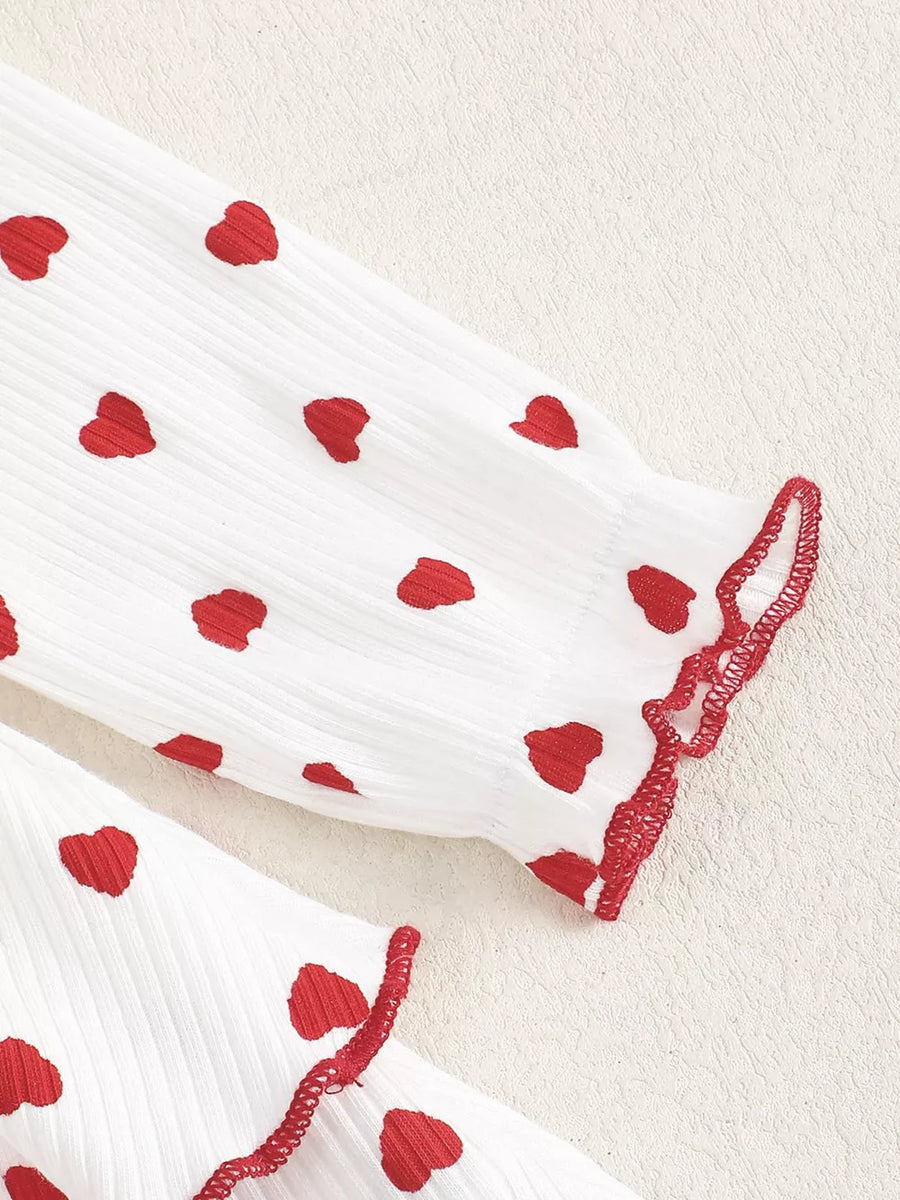 White cotton baby dress with red hearts and ruffled trim.