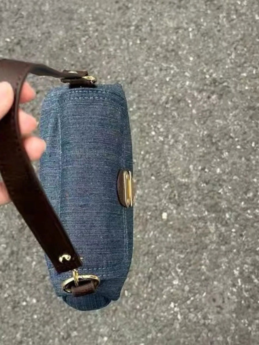 Mini denim shoulder bag with brown leather strap and gold hardware.