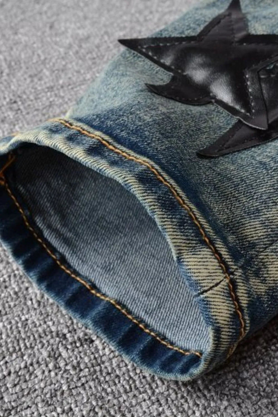 Slim-fit denim jeans in medium wash with black star appliqué detail.