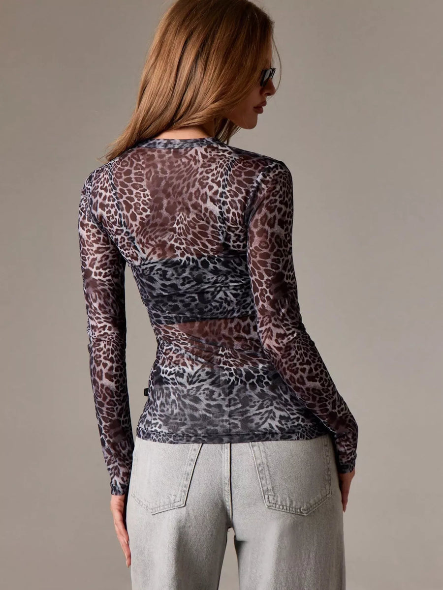 Sheer long-sleeve animal print top in leopard pattern, styled with a bra and light wash jeans.