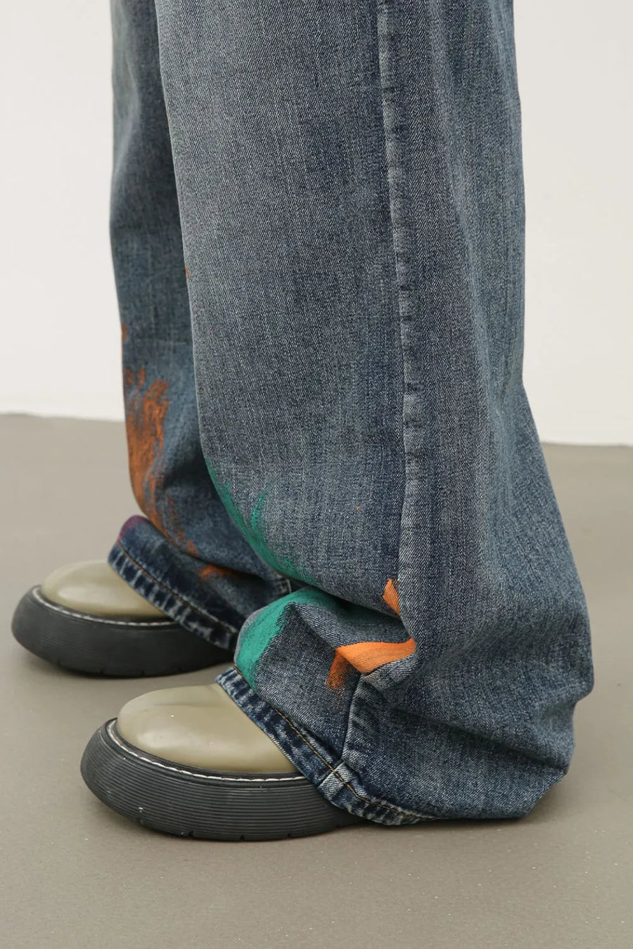 Painterly wide-leg jeans in medium wash denim with artistic orange and green paint splatters.