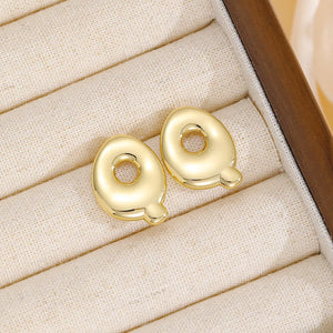 Alphabetical sculpted stud earrings in gold, featuring the letter Q.