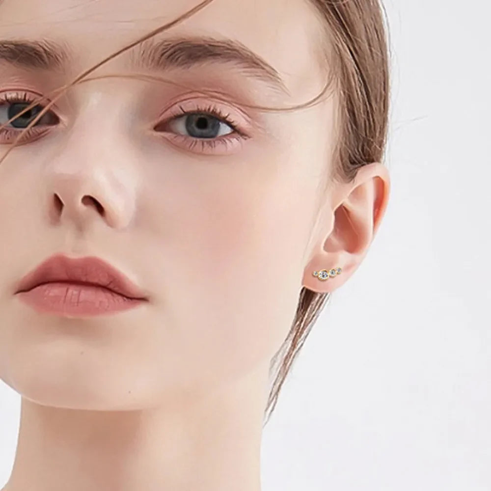 Gold ear climbers with three clear stones, styled on an adult model.