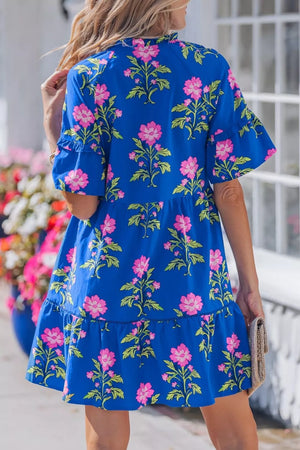 Tiered floral cotton dress in blue with pink flowers, short ruffled sleeves, and a ruffled hem.