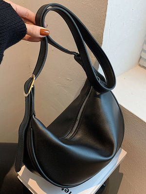 Black pu leather crescent crossbody bag with silver zipper detail and gold buckle.