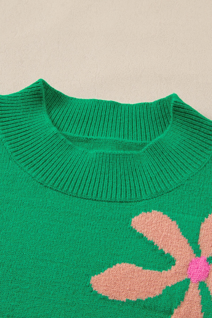Green knit sweater with a large floral print and ribbed crew neck.