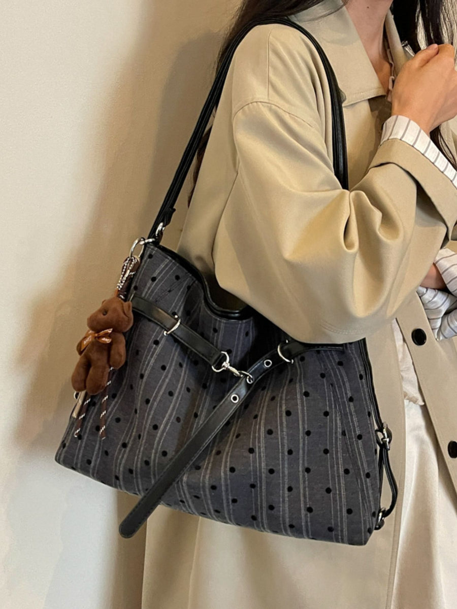 Black handbag featuring buckle straps and polka dot, striped