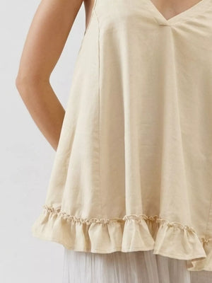 Ivory camisole with adjustable tie straps and ruffled hem detail.