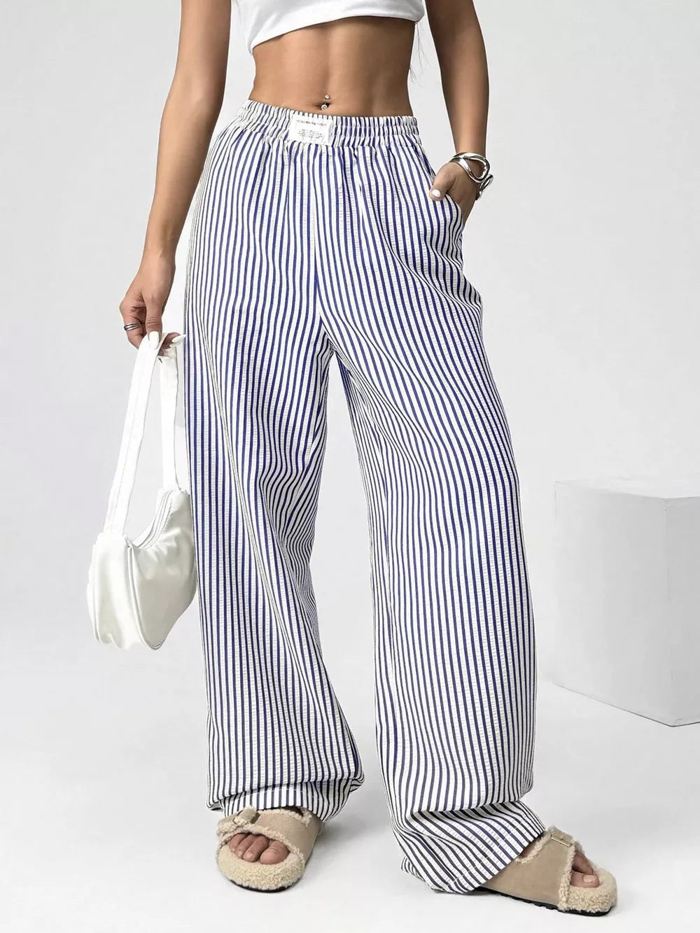 Navy striped high-waisted wide-leg pants with drawstring detail and pockets.