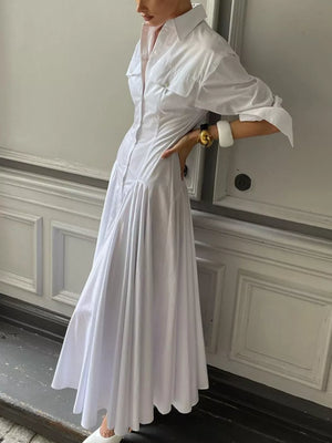 White cotton shirt dress with button front, chest pockets, and a flowing maxi skirt.