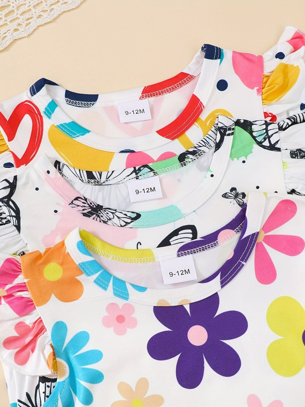 Baby girls' ruffled sleeve one-pieces with colorful floral and butterfly prints.