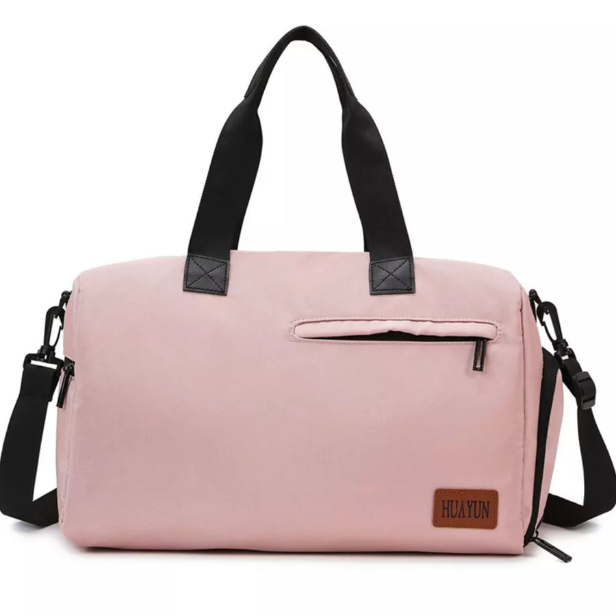 Pink nylon duffel bag with black straps, front zip pocket, and adjustable shoulder strap.