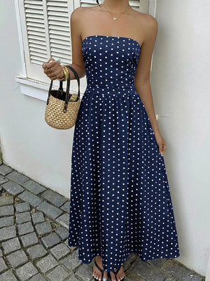 Navy polka dot A-line maxi dress with strapless neckline and cinched waist.
