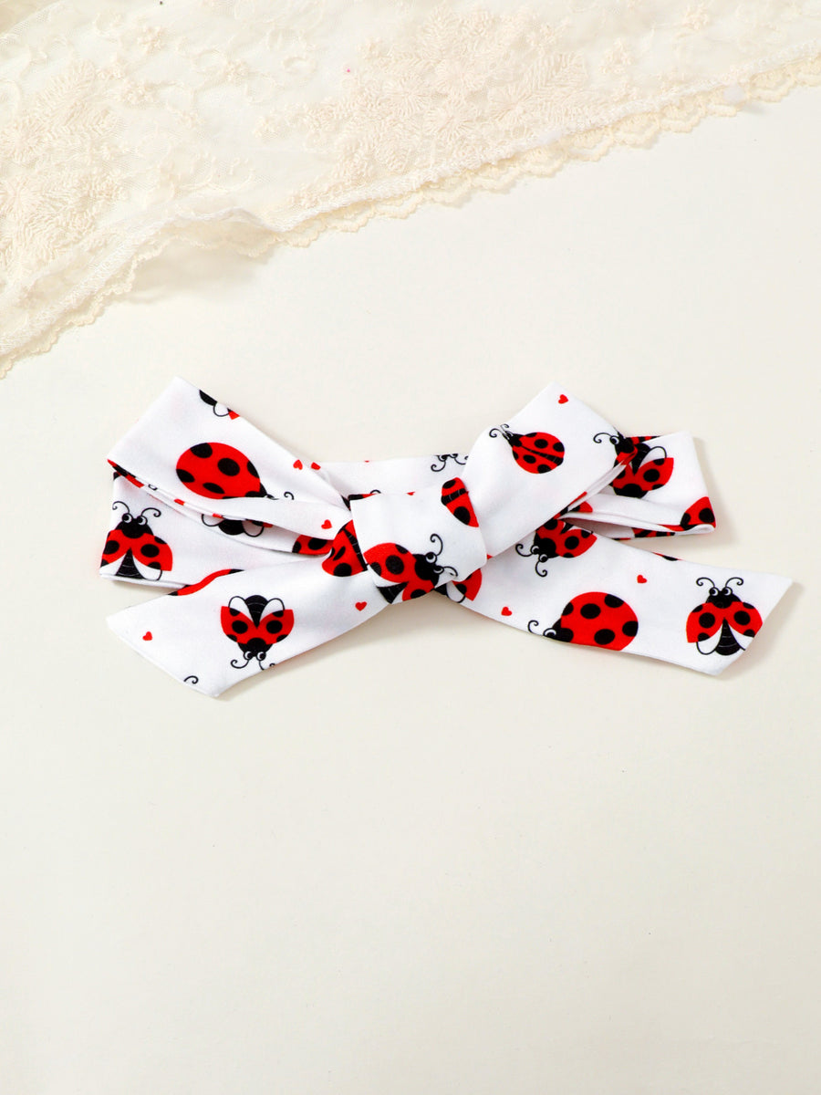 White baby headband with red ladybug print and bow detail