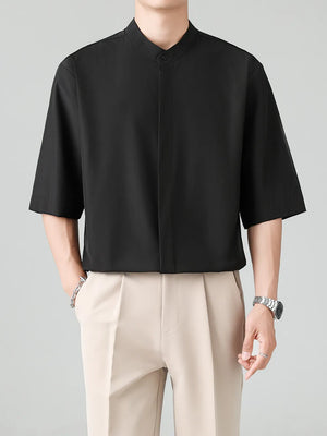 Black oversized mandarin collar half-sleeve shirt with button detail.