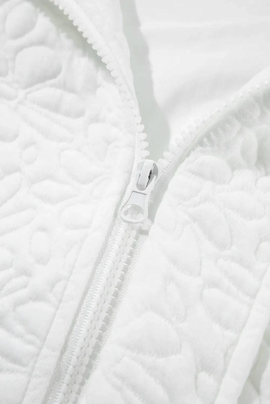 White bomber jacket with all-over quilted floral pattern and white zipper detail.