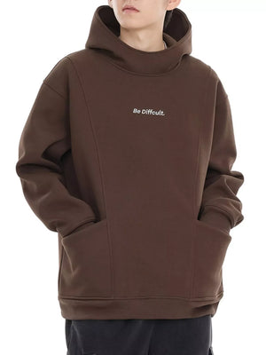 Oversized coffee graphic hoodie with "Be Difficult." text and front pocket.