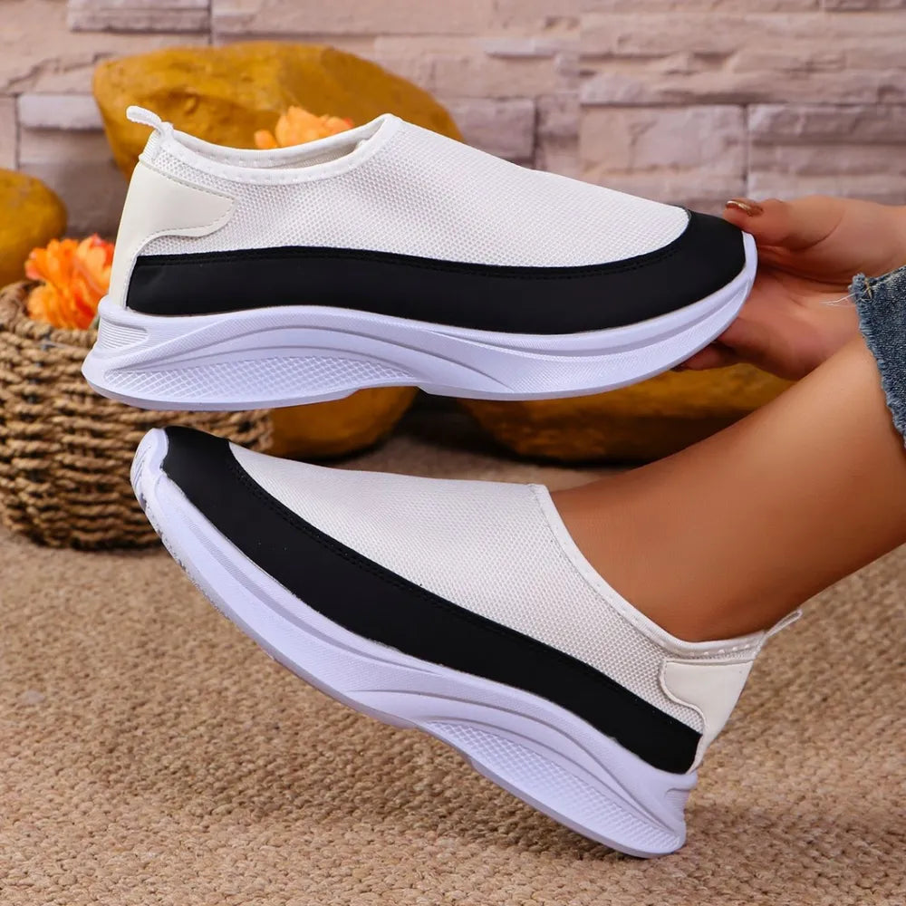 White mesh slip-on sneakers with black stripe detail and white sole.