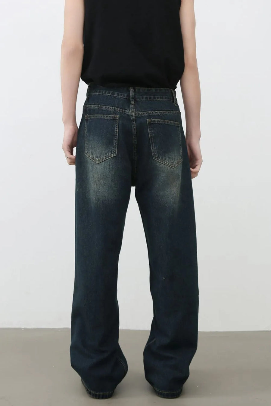 Distressed dark wash wide-leg denim jeans with knee tears and a relaxed fit.