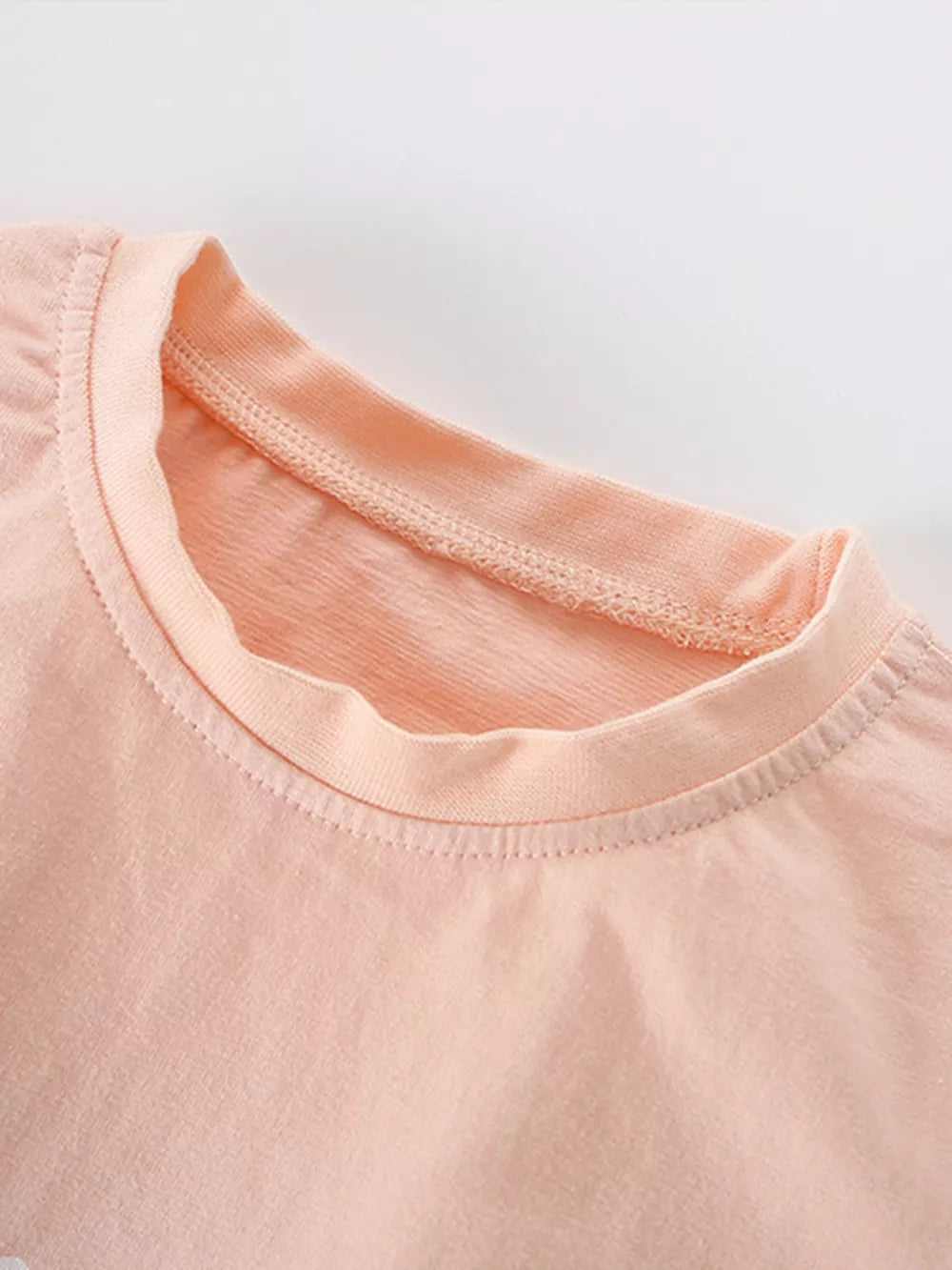 Peach cotton toddler t-shirt with crew neck and detailed stitching.