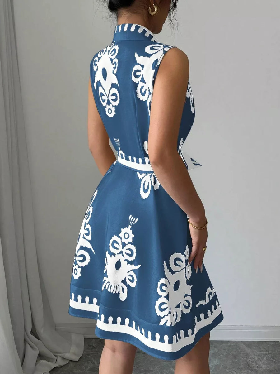 Dusty blue a-line dress with white pattern, sleeveless, collared, and belted waist.