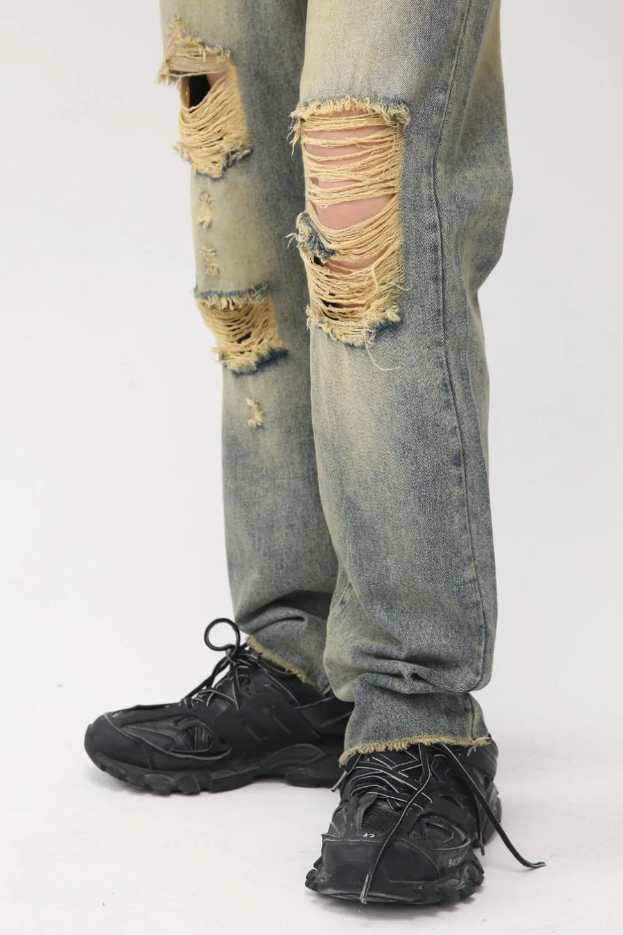 Baggy denim jeans in medium wash with shredded knees and distressed details.