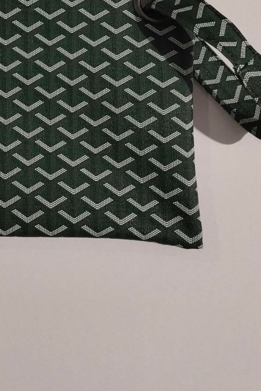 Plaid print wristlet clutch bag in army green with white geometric pattern and grommet detail.