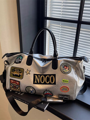 Metallic patchwork travel bag with textured finish and various embroidered patches.