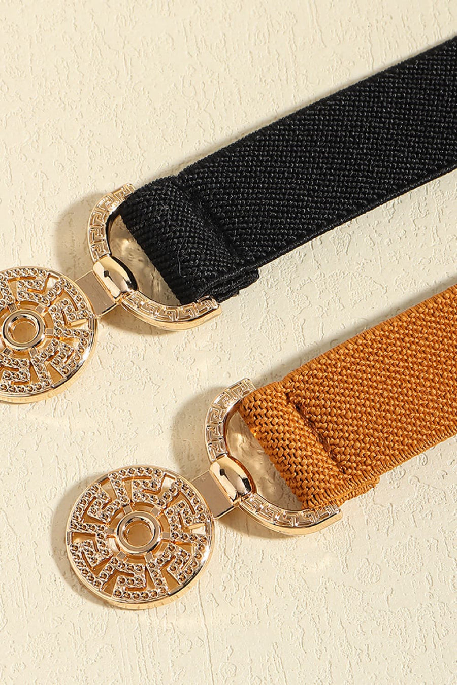 Elasticated belts in black and caramel with ornate gold medallion buckles.