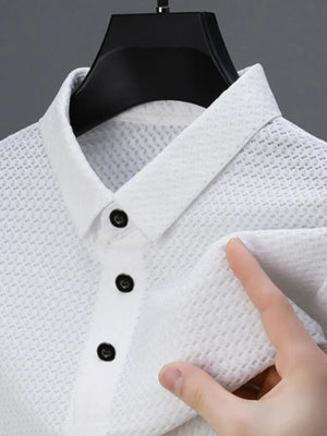 White textured pique polo shirt with refined collar and dark buttons.