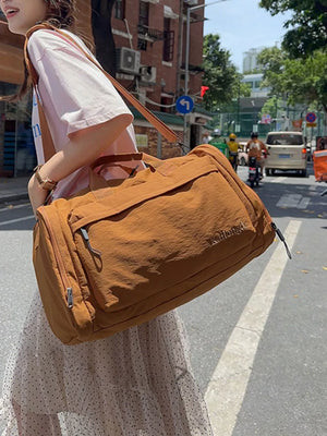 Brown Oxford cloth travel bag with detachable strap and embroidered detail.