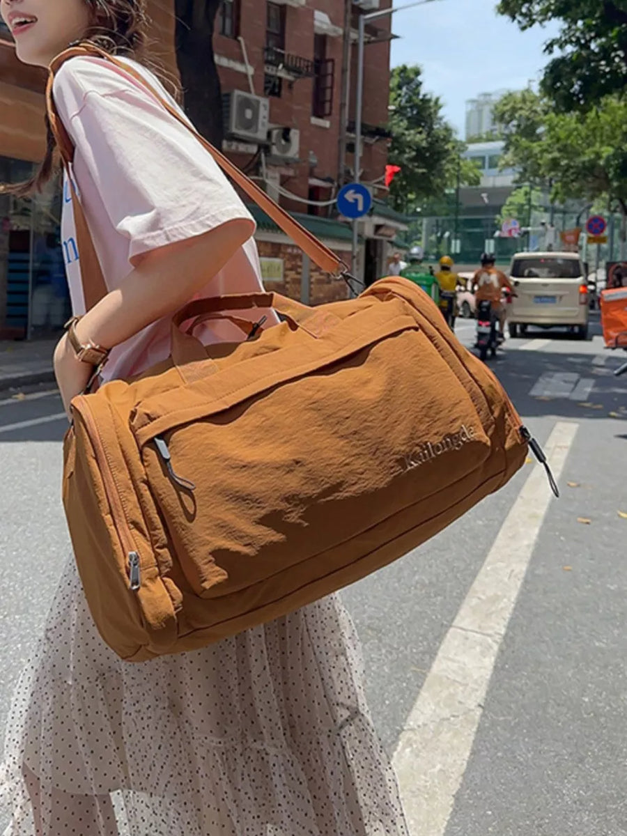 Brown Oxford cloth travel bag with detachable strap and embroidered detail.