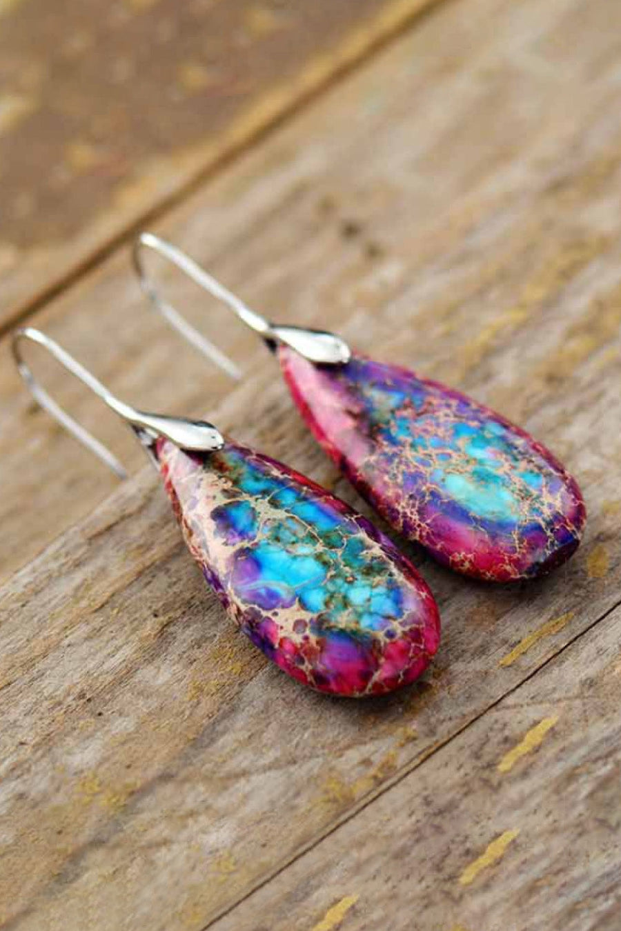 Teardrop jasper drop earrings in gold/multi and silver/multi feature vibrant blue, pink, and purple marbled patterns.