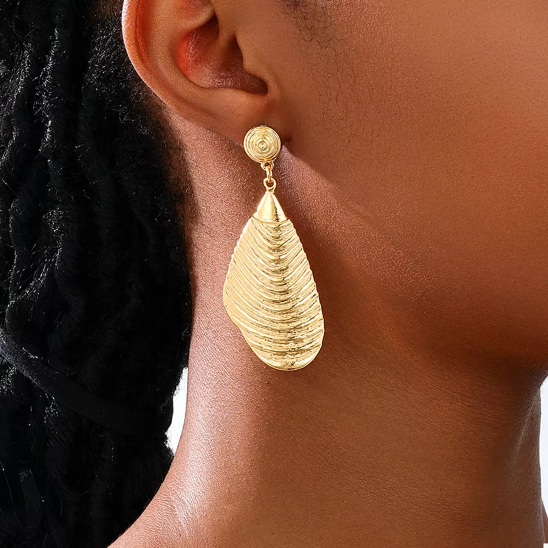 Textured gold dangle earrings with a teardrop-shaped, ridged pendant.