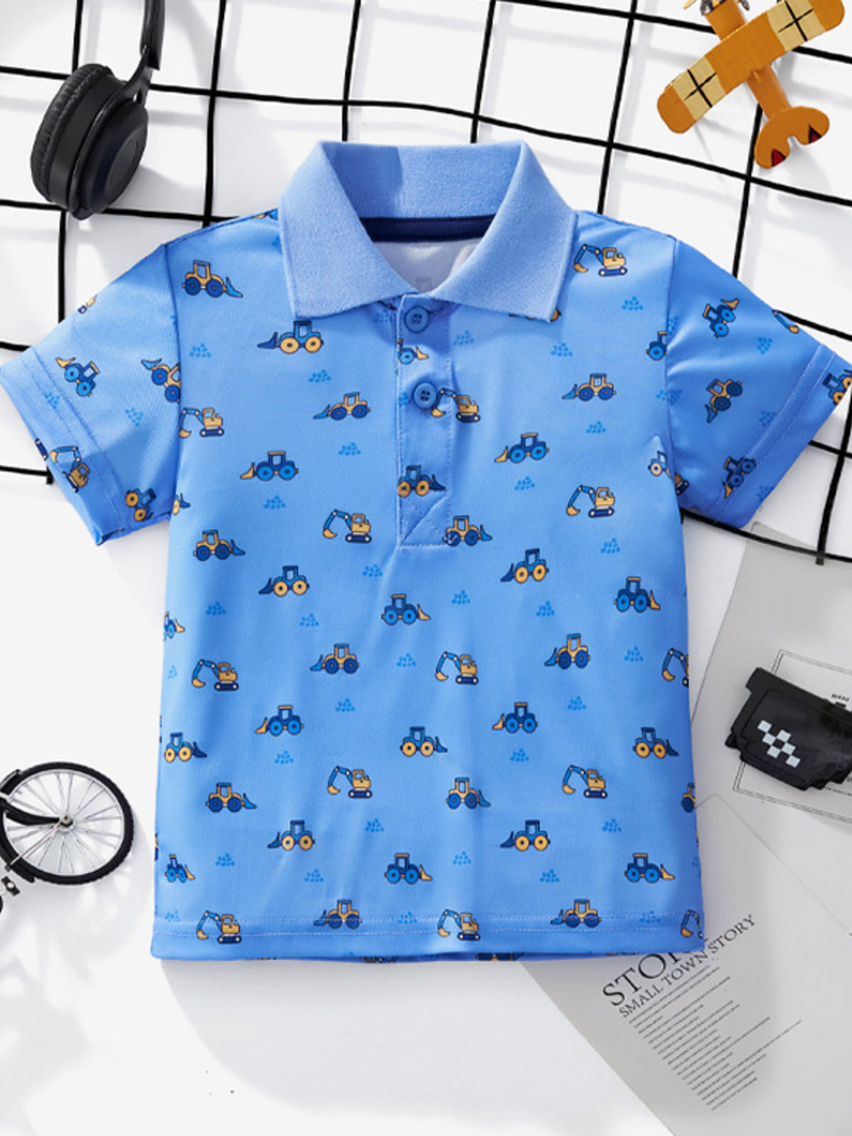 Toddler blue polo shirt with allover excavator print, short sleeves, and button placket.