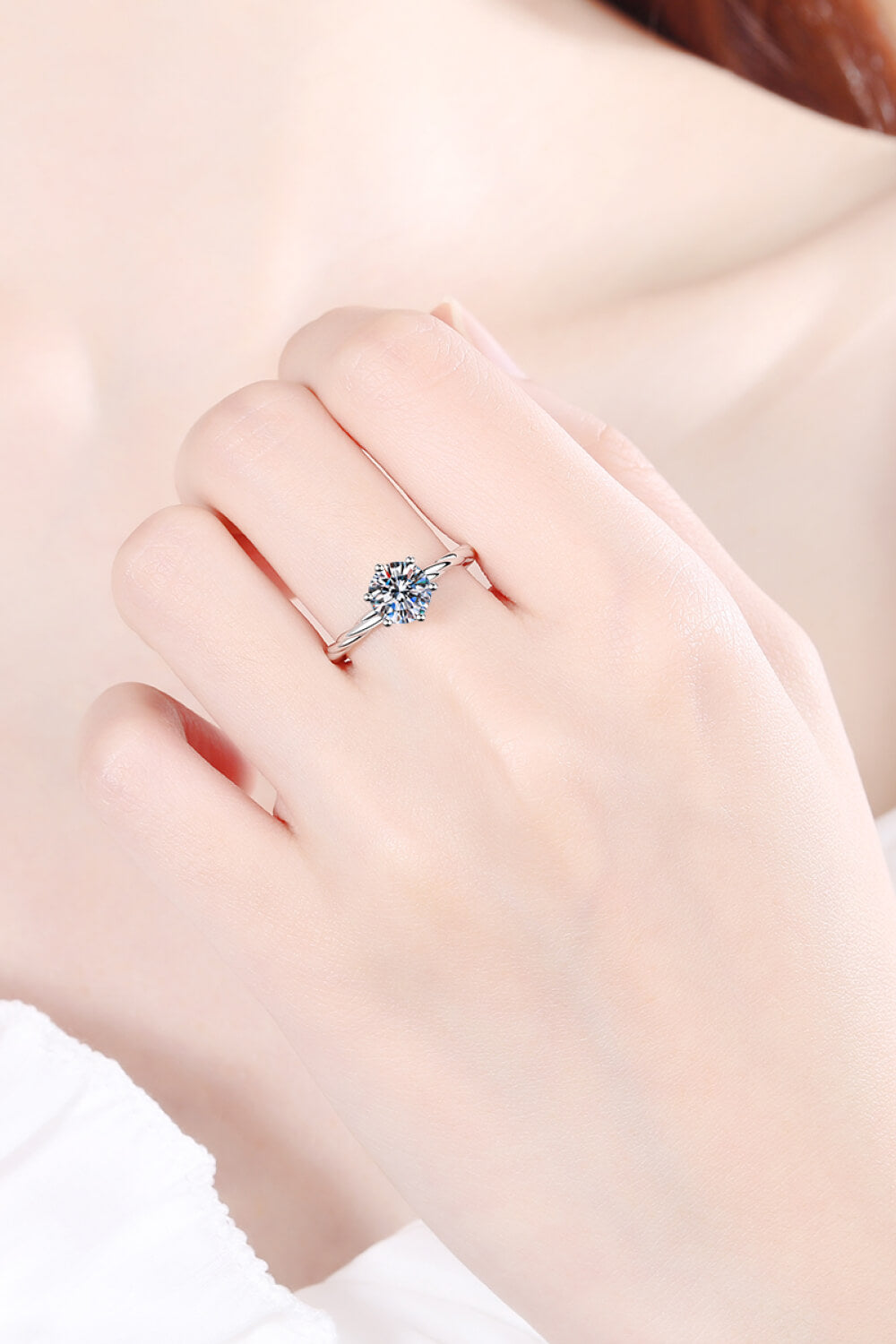Silver moissanite solitaire ring with twisted band detail.