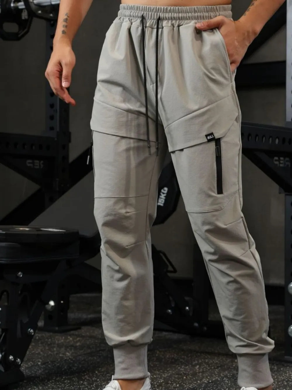 Gray technical joggers with zip pockets and elastic cuffs.